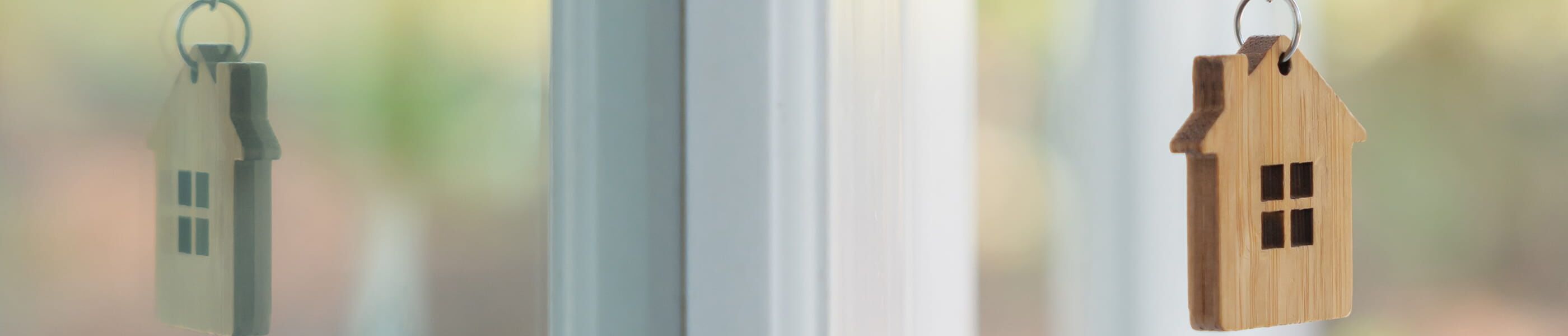 Schlüsselanhänger in Hausform aus Holz vor Fenster