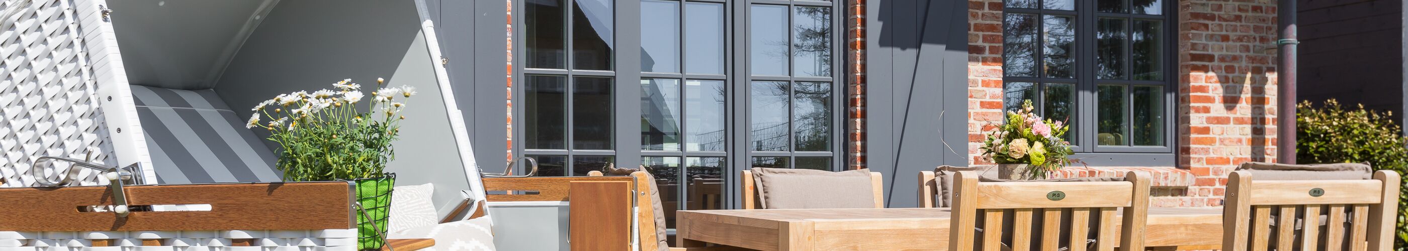 Sonnenterrasse einer Ferienwohnung auf Sylt – Holzdeck mit Strandkorb und Gartentisch